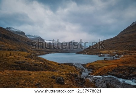Panoramic view of the fjord of Funningsfjordur with dramatic cloudy sky and snow-covered mountains Faroe Islands, Denmark, Europe. November 2021