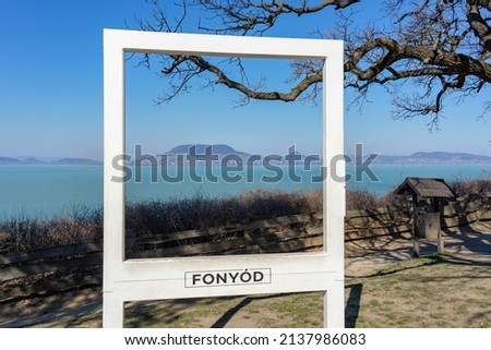 beautiful szaplonczay promenade with lake balaton landscape in Fonyód Hungary with badacsony hill in white photo frame with Fonyod sign 