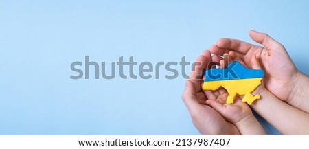 Shape of the map of Ukraine in yellow and blue colors in the hands of an adult and a child. Banner with copy space.