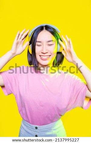 Young asiatic woman listening music headphones isolated with confidence and smiling 