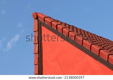 The red roof was built with tiles.  isosceles shape.