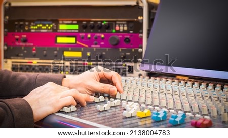 sound engineer hands working on audio mixing console in studio. post production, broadcasting, recording concept