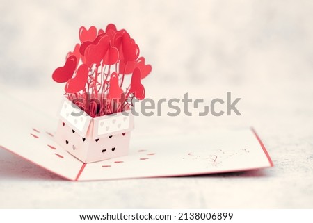 A red pop up card with heart shapes bursting out of box with heart shaped cut out on box, space for text Royalty-Free Stock Photo #2138006899