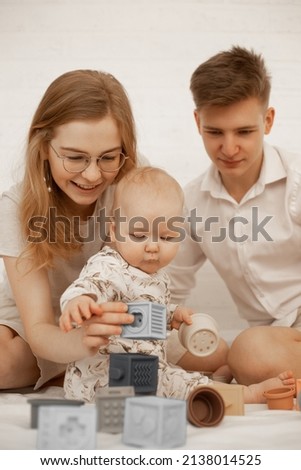 Vertical photo of happy encouraging family woman in glasses, man, baby playing games. Creativity and imagination. 