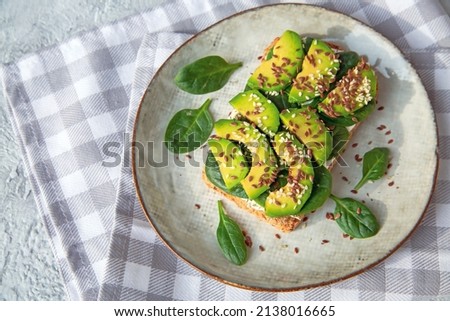 Toast with avocado, cottage cheese, spinach, sesame seeds, flax seeds. Healthy food rich in fiber, trace elements, omega acids, unsaturated lipids. Royalty-Free Stock Photo #2138016665