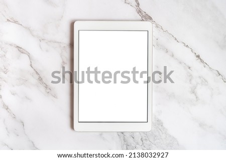 digital tablet computer with vertical white blank digital screen for mockup or space for text on a gray marble background. top view, flat lay