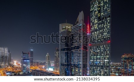 Aerial view of Dubai International Financial District with many skyscrapers night timelapse. Starry sky and illumination turning off. Dubai, UAE.
