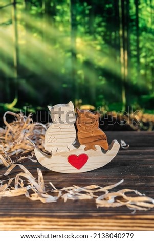 Wooden puzzle in the form of a family of handmade owls on the background of the forest.