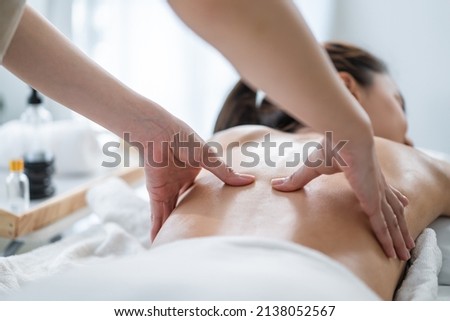 Asian young woman feeling happy and relax during back massage with oil. Attractive beautiful girl lying on massage table, getting physiotherapy from masseuse for skin and body care in spa beauty salon Royalty-Free Stock Photo #2138052567