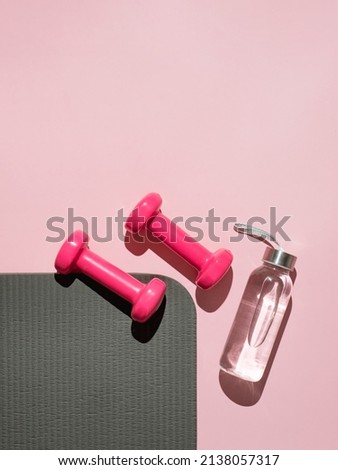 Stylish gray, water bottle and pink fitness training and gym flat lay. Top view of gray sport mat and pink dumbbells on pink background. Set for pilates, fitness with copy space. Vetical Royalty-Free Stock Photo #2138057317
