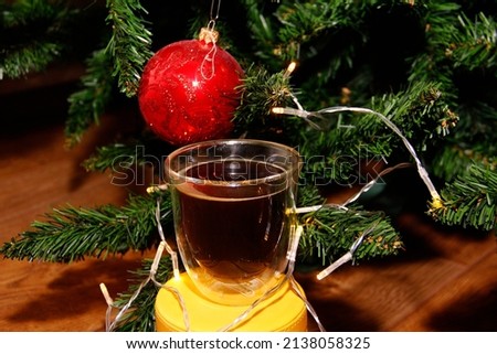 A transparent cup with a double bottom on the background of a Christmas tree with Christmas toys