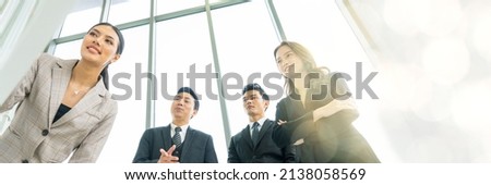 Four young men and women in Asian suits are meeting at a company board. Happy and excited about work. The concept is Finance, Marketing, Accounting web banner with copy space on right