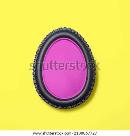 Egg shape made of car tire on a bright yellow background  with a pink fill. Minimal easter concept.  Flat lay. Royalty-Free Stock Photo #2138067727