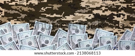 US dollar bills on fabric with texture of Ukrainian military pixeled camouflage. Cloth with camo pattern in grey, brown and green pixel shapes. Official uniform of Ukrainian soldiers close up Royalty-Free Stock Photo #2138068113
