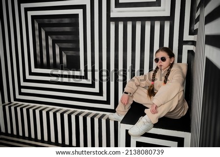 Portrait stylish girl sit in a black and white room with stripes