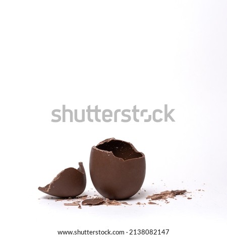 Cracked chocolate easter egg on light background, copy space. Broken milk chocolate egg with lid. Chocolate Easter concept. Royalty-Free Stock Photo #2138082147
