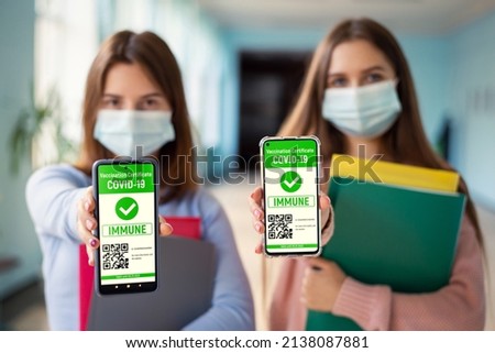 Two students showing screens of phones with digital certificates of successful vaccination. Vaccination among students concept