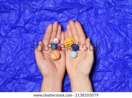 Hands with small solar system planets on a blue background