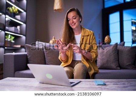 Happy joyful smiling casual satisfied woman learning and communicates in sign language online using laptop at cafe 
