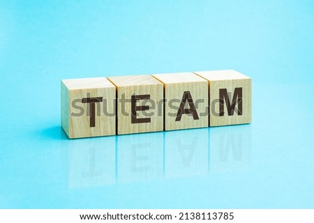 Team - word written on wooden blocks. text is written in black letters and is reflected in the mirror surface of the table, blue background. business concept for your design