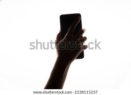 Female arm silhouette holding smart phone.