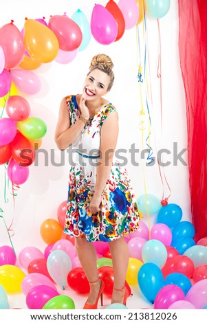 Young woman at a party in a colorful setting with many balloons