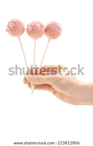 Pink cake pops in hand isolated on white background