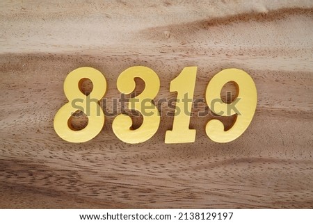 Wooden  numerals 8319 painted in gold on a dark brown and white patterned plank background.