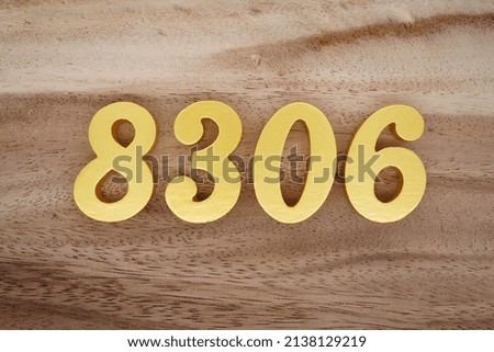 Wooden  numerals 8306 painted in gold on a dark brown and white patterned plank background.