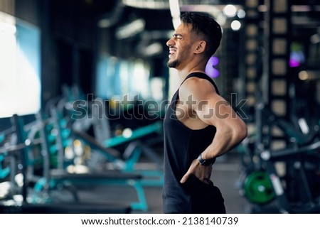 Sport Trauma. Young Arab Male Athlete Suffering Lower Back Pain During Training At Gym, Middle Eastern Sportsman Massaging Sore Zone And Screaming With Ache, Having Injured Lumbar Spine, Copy Space Royalty-Free Stock Photo #2138140739