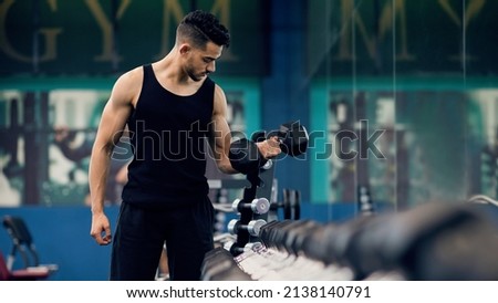 Bodybuilding Concept. Portrait Of Muscular Young Arab Man Training With Dumbbells At Gym, Confident Middle Eastern Bodybuilder Working Out With Light Weights In Sport Club, Panorama, Copy Space Royalty-Free Stock Photo #2138140791