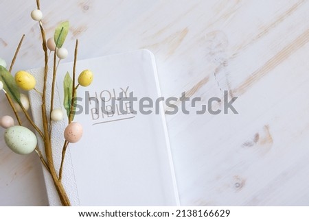 White bible and decorative branch with easter eggs on a white wood background with copy space Royalty-Free Stock Photo #2138166629
