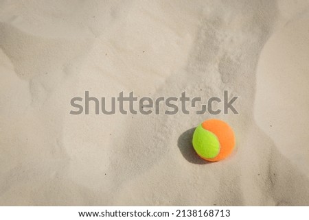 Tennis ball on the sand at the beach close up