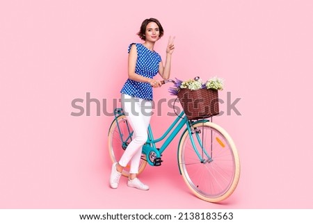 Full length photo of cool millennial brunette lady drive bicycle show v-sign wear blouse pants sneakers isolated on pink background Royalty-Free Stock Photo #2138183563