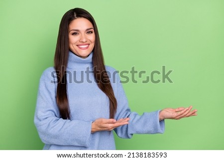 Photo of pretty young brunette lady show promo wear blue sweater isolated on green color background