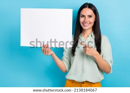 Photo of young girl indicate finger paper poster advert recommend suggest isolated over blue color background