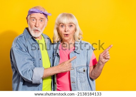 Photo of shocked boyfriend girlfriend pensioner dressed denim outfit pointing empty space isolated yellow color background