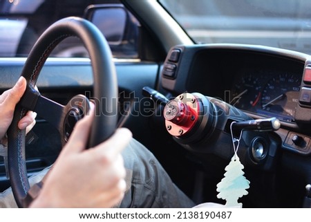 Person removing steering wheel from stock to protect car from theft. Close up with hands holding steering wheel detached from steering column in older car to prevent crime Royalty-Free Stock Photo #2138190487