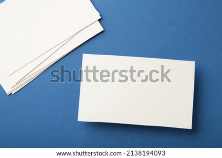 Blank white business cards on blue paper background. Mockup for branding identity. Template for graphic designers portfolios.