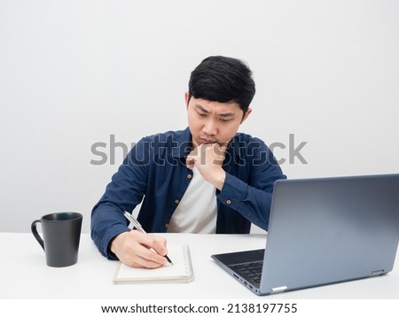 Man writing at notebook on the desk with laptop white background