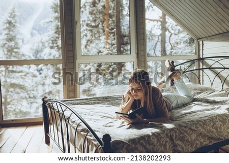 A beautiful girl is reading an e-book. Teen girl is reading a book. High quality photo