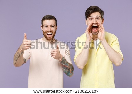 Two young men friends together in casual t-shirt shout with hands near mouth scream news show thumb up gesture isolated on purple color background studio People lifestyle concept. Tattoo translate fun