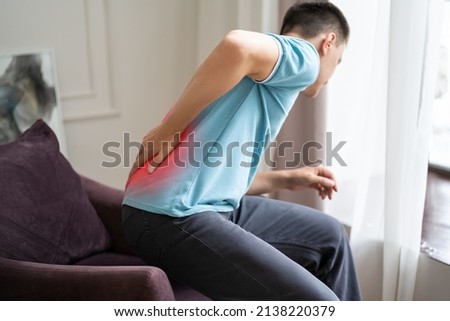 Back pain, kidney inflammation, man suffering from backache at home, painful area highlighted in red Royalty-Free Stock Photo #2138220379