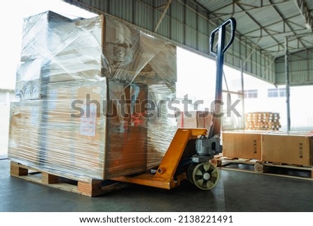 Packaging Boxes Wrapped Plastic Film on Pallets Rack with Hand Pallet Truck. Supply Chain Goods. Storehouse Commerce Cargo Shipment. Shipping Warehouse Logistics.	
