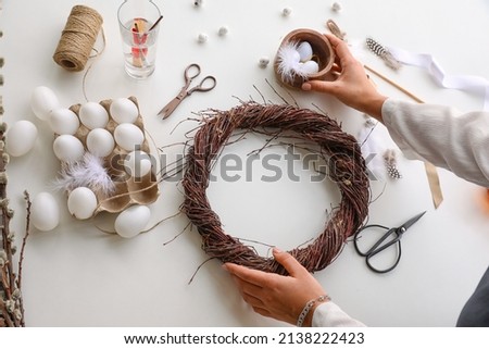 Woman making Easter wreath on light table, closeup