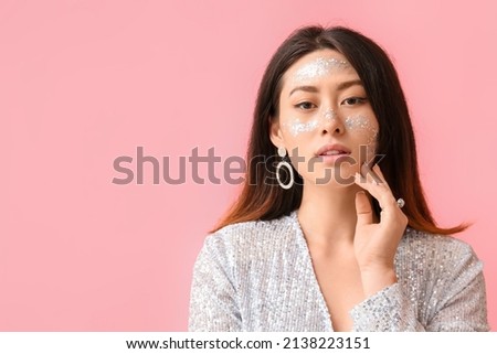 Portrait of fashionable Asian woman with glitter makeup on color background