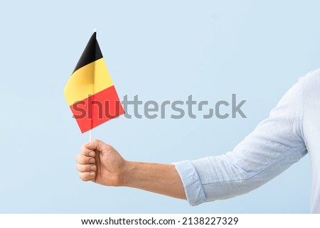 Male hand with Belgian flag on light background