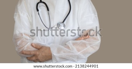 elder woman, doctor, in white medical robe, with hands one over another. nurse, medical assistant is wearing a black stethoscope on neck. medical disposable clothing. virus, other diseses protection