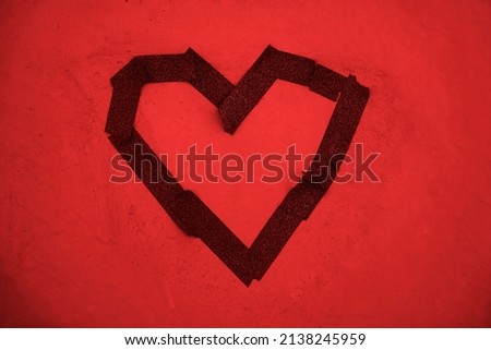 red  heart made from pieces of electrical tape and glued on a dirty red wall