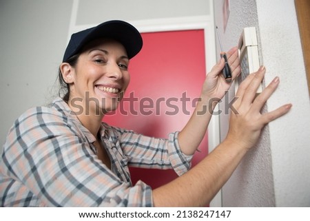 happy woman plumber fixing a thermostat